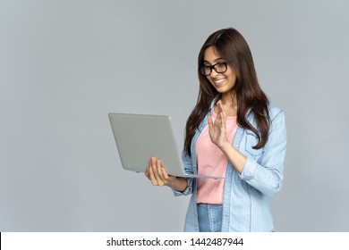 Happy Indian Girl Holding Using Laptop Looking At Computer Screen Make Conference Online Call, Smiling Young Hindu Woman User Waving Hand  Doing Internet Video Chat Isolated On Grey Studio Background