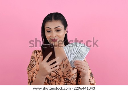 Happy Indian Girl with Phone and Money in Hand - Indian Currency notes of 500 Rupees.