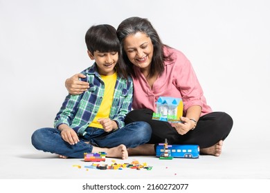 Happy Indian Grandmother And Grandson Playing With Colorful Toys, Isolated On White Studio Background, Grandma Teaching Male Grandchild, Learning Concept.