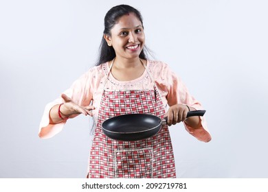 Feliz ama de casa india sosteniendo una cuchara de fritura en la mano y usando una gorra de chef que exhibe varios estados de ánimo del chef de la casa. La mujer india está usando un delantal y un atuendo indio.