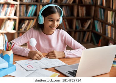 Happy indian latin preteen girl school pupil wearing headphones distance learning online at virtual class with teacher tutor on laptop by video conference call, watching tv lesson at home. - Powered by Shutterstock