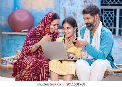 Happy indian little girl child using laptop while sitting with her father and mother. Village parents motivate support their daughter for online education. digital india. Man point finger at computer