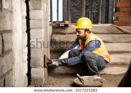 Happy Indian male construction worker constructing brick wall - hard working concept, manual labour Imagine de stoc © 