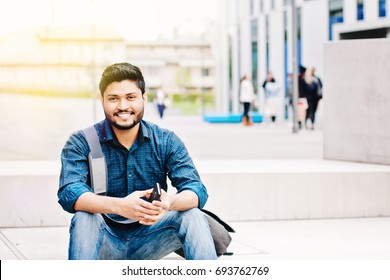 Happy Indian Male Student Holding Smartphone Sitting Outdoor