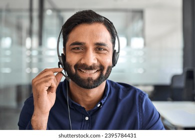 Happy Indian man call center agent wearing headset in office. Smiling male contract service representative telemarketing operator looking to camera working in customer support. Headshot portrait. - Powered by Shutterstock