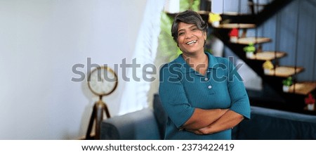 Happy Indian middle aged smiling businesswoman looking at camera posing for video. Independent grey-haired adult female feminism worker standing confidently folding hand facing cam. Head shot portrait