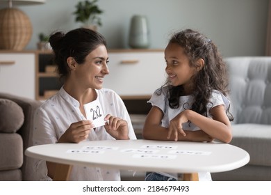 Happy Indian mom helping kid to study math, learning multiplication table, showing using flash cards, playing educational game, doing school home task together