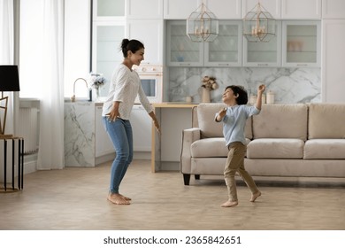 Happy Indian mother with 5s son dancing at home together, spending leisure time in living room, smiling young mom and adorable boy child moving to favorite music, family engaged in funny activity - Powered by Shutterstock