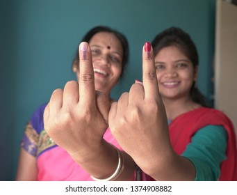 A happy indian mother and daughter shows her ink-marked fingers after casting vote in Election. Selective focus.