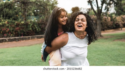 Happy indian mother having fun with her daughter outdoor - Soft focus on mom face
