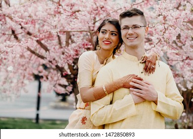 Happy indian newlyweds spend time together in the park with sakura