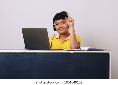 Happy Indian School Pupil Or Boy Wearing Headphones Raising Hand Distance Learning Online At Virtual Lesson Class