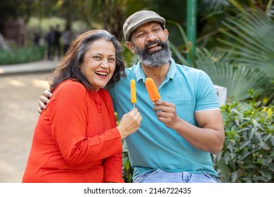 Happy indian senior couple eating ice lolly or ice cream in a park outdoor, old mature people enjoy retirement life. summer holidays. - Shutterstock ID 2146722435