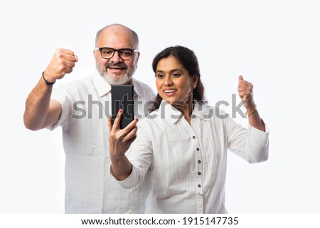 Happy Indian senior couple using smartphone. Standing isolated against white background