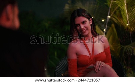 Happy Indian smiling couple sitting on chair talking late night dating outdoor home. Beautiful husband wife celebrate anniversary spend time enjoy holiday weekend together outside house