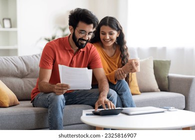 Happy Indian Spouses Checking Financial Documents And Calculating Family Budget At Home, Cheerful Eastern Couple Sitting At Table In Living Room, Reading Loan Papers Or Counting Monthly Expenses - Shutterstock ID 2325816907