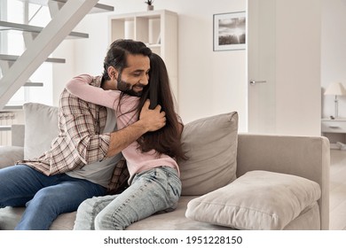 Happy Indian Teen Child Daughter Embracing Dad At Home On Fathers Day. Smiling Ethnic Family Young Daddy Hugging Teenage Kid Girl Bonding Sitting On Sofa At Home Enjoying Sweet Tender Love Concept.