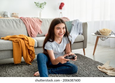 Happy Indian Teenager With Joystick Playing Online Computer Games In Messy Room During Covid Lockdown. Cheerful Adolescent With Controller Engaged In Video Gaming At Home