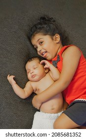 
Happy Indian Toddler Girl Playing With Her Newborn Sister.Toddler Kid Meeting New Sibling. Family With Children At Home. Love, Trust And Tenderness