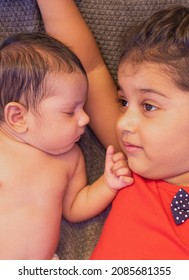 
Happy Indian Toddler Girl Playing With Her Newborn Sister.Toddler Kid Meeting New Sibling. Family With Children At Home. Love, Trust And Tenderness