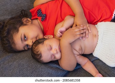 
Happy Indian Toddler Girl Playing With Her Newborn Sister.Toddler Kid Meeting New Sibling. Family With Children At Home. Love, Trust And Tenderness