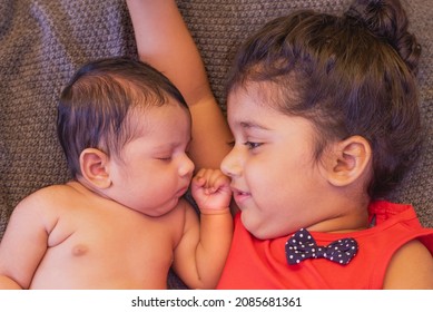 
Happy Indian Toddler Girl Playing With Her Newborn Sister.Toddler Kid Meeting New Sibling. Family With Children At Home. Love, Trust And Tenderness