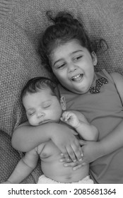 
Happy Indian Toddler Girl Playing With Her Newborn Sister.Toddler Kid Meeting New Sibling. Family With Children At Home. Love, Trust And Tenderness