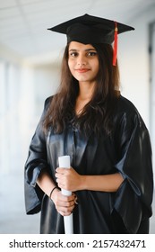 Happy Indian University Student In Graduation Gown And Cap Holding Diploma Certificate.