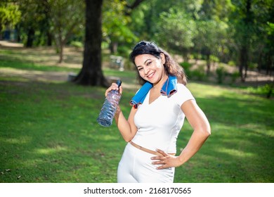 Happy Indian Woman Athlete Takes A Break Holding Water Bottle Wearing White Cloths, Asian Female Standing On A Hot Day In The Park.