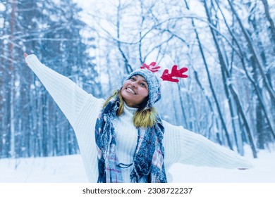 Happy indian woman having fun and enjoying first snow wear fun hat deer horn - Powered by Shutterstock