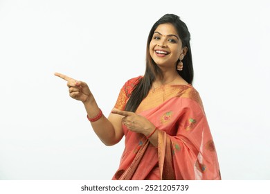 Happy Indian woman pointing finger to empty space and wearing traditional pink colorful saree with facial expressions on white background, Advertisement and promotion. - Powered by Shutterstock