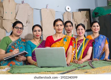 Happy Indian woman using laptop by sewing machine at textile factory - Powered by Shutterstock