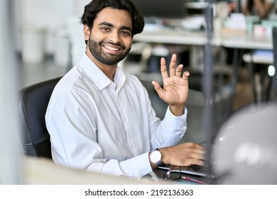 Happy Indian Young Business Man Professional Manager, Office Employee Worker, Programmer Or Analyst Working Online On Laptop Computer Looking At Camera Waving Hand Sitting At Workplace, Portrait.