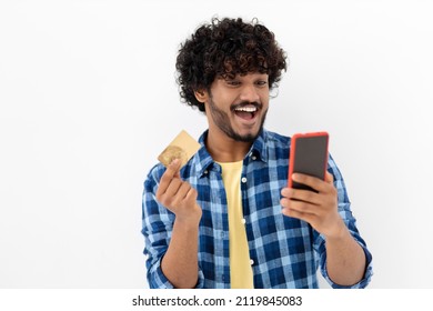 Happy Indian young man doing online shopping using mobile phone and credit card, beautiful excited male feels euphoria from a long-awaited purchase the Internet, smiling