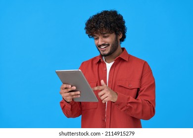 Happy indian young man using digital tablet isolated on blue background. Smiling ethnic student guy holding pad remote learning in app, studying or communicating, surfing online, reading e book.