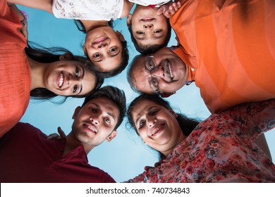 Happy Indian/Asian Modern Family Forming A Circle And Looking Down At Camera