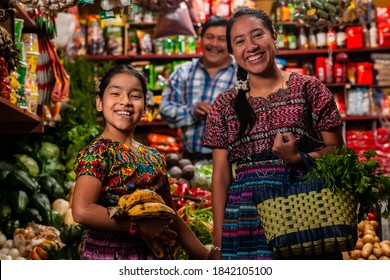 Happy indigenous girls looking at the camera in a grocery store and a salesman behind them.