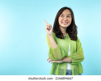 A happy Indonesian (Asian) girl caught an idea on a blue isolated background