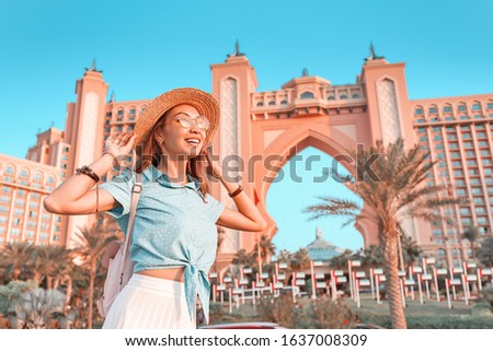 Happy indonesian girl traveler relaxing near famous luxury Atlantis hotel building on a Jumeirah Palm Island in Dubai, UAE