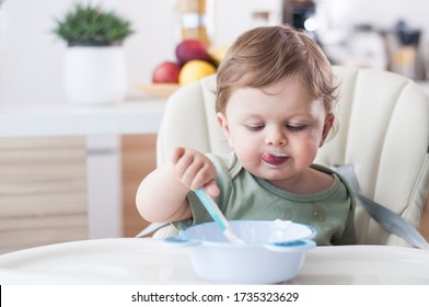Happy infant baby boy spoon eats itself
