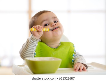 Happy infant baby boy spoon eats itself - Shutterstock ID 631322687