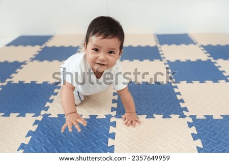 happy infant baby crawling on play mat or jigsaw floor