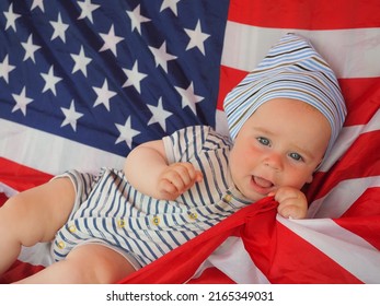  Happy Infant Plays Swinging On A Swing Against The Background Of The National Flag Of The United States Of America.