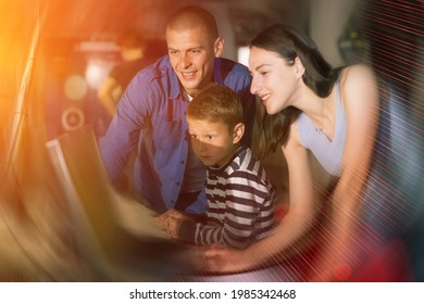 Happy Interested Family With Teen Sons Trying To Get Out Of Closed Space Of Escape Room Stylized As Abandoned Bunker, Using Computer. Toned Image With Color Visuals..