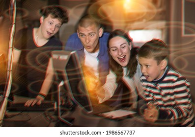 Happy Interested Family With Teen Sons Trying To Get Out Of Closed Space Of Escape Room Stylized As Abandoned Bunker, Using Computer. Toned Image With Color Visuals..