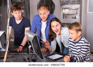 Happy Interested Family With Teen Sons Trying To Get Out Of Closed Space Of Escape Room Stylized As Abandoned Bunker, Using Computer