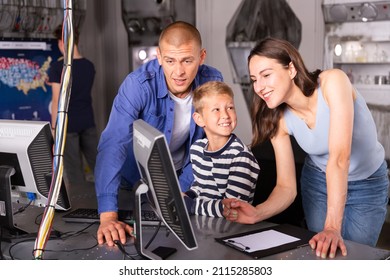 Happy Interested Family With Teen Sons Trying To Get Out Of Closed Space Of Escape Room Stylized As Abandoned Bunker, Using Computer