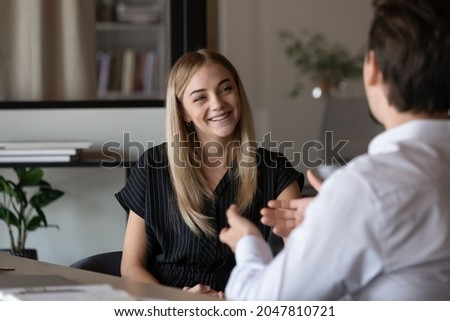 Happy intern listening to mentor, consulting advisor, talking to supervisor, smiling, laughing. Job candidate meeting with employer for interview, discussing vacancy, making good first impression