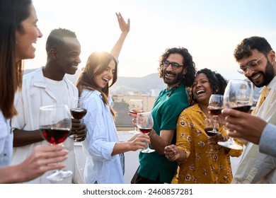 Happy international community enjoying party dance with glass of red wine at sunset rooftop party. Girl dancing with raised hands at disco outdoors with friends. Beautiful people having fun together  - Powered by Shutterstock