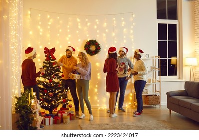 Happy international friends celebrate Christmas together decorate fir-tree with lights, bubbles. Happy multiracial young people celebrate New Year at home. Winter holidays, party concept. - Powered by Shutterstock